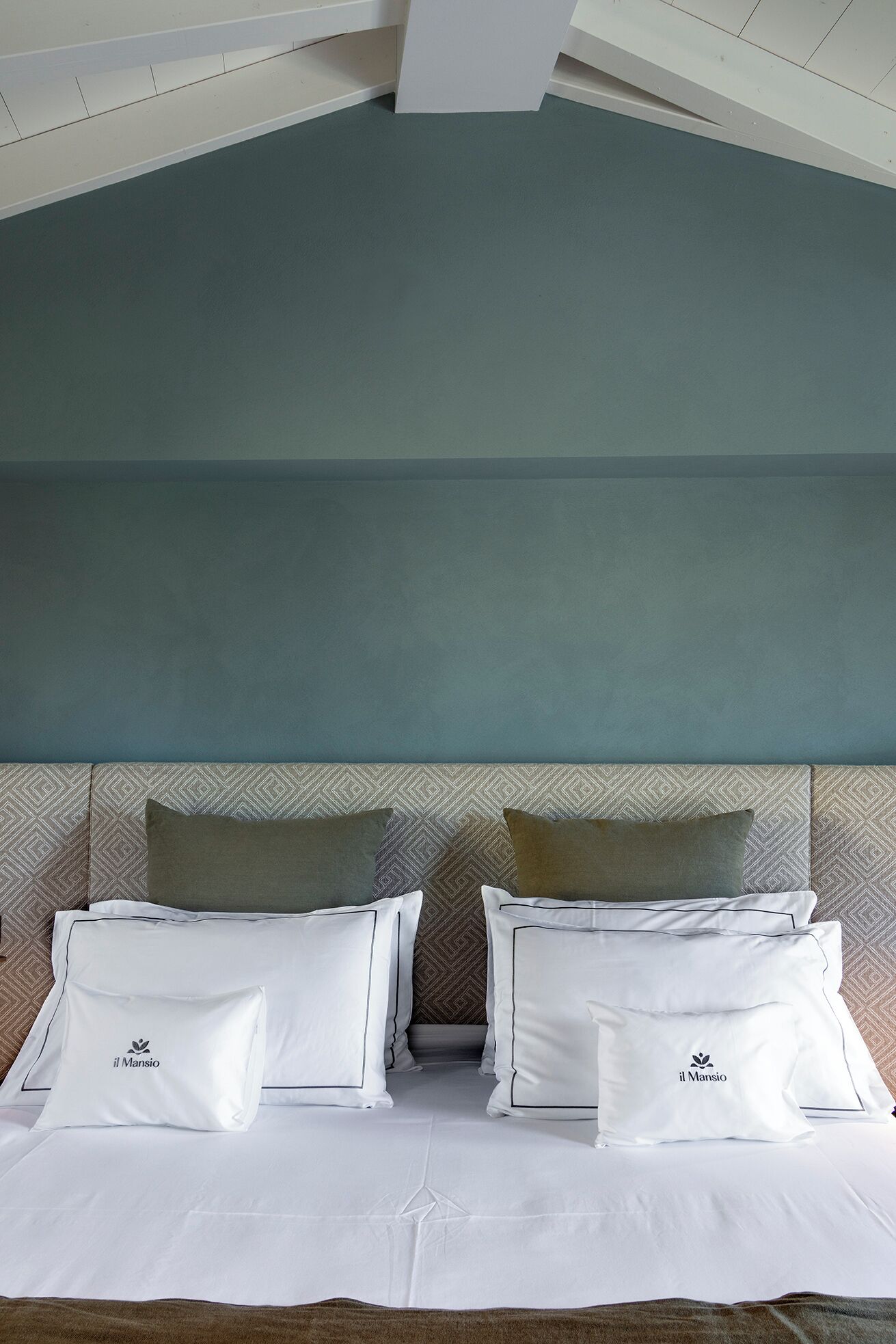 Una habitación de hotel con cama, almohadas y cabecero.