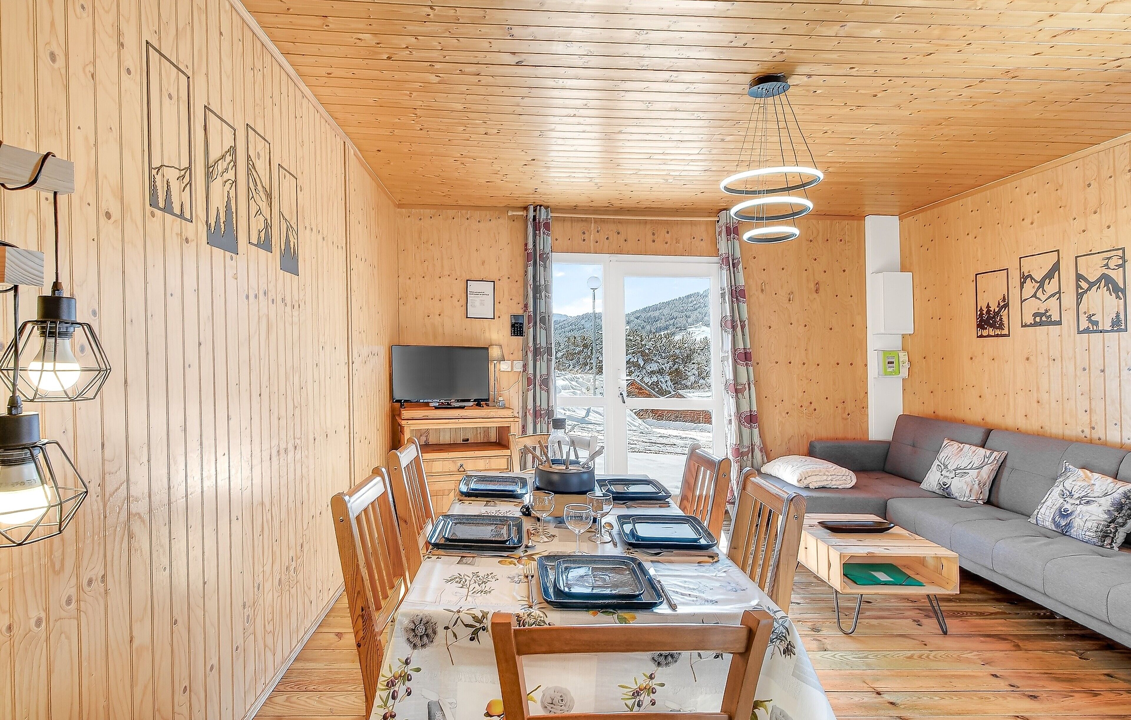Ein Holzinterieur mit Essplatz, einer Couch und einem Fernseher.