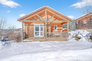 A wooden cabin with a porch, a door, and a window.