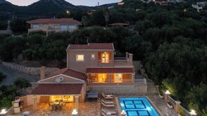 Ein zweistöckiges Haus mit Swimmingpool, Steinterrasse und Blick auf die umliegenden Hügel.