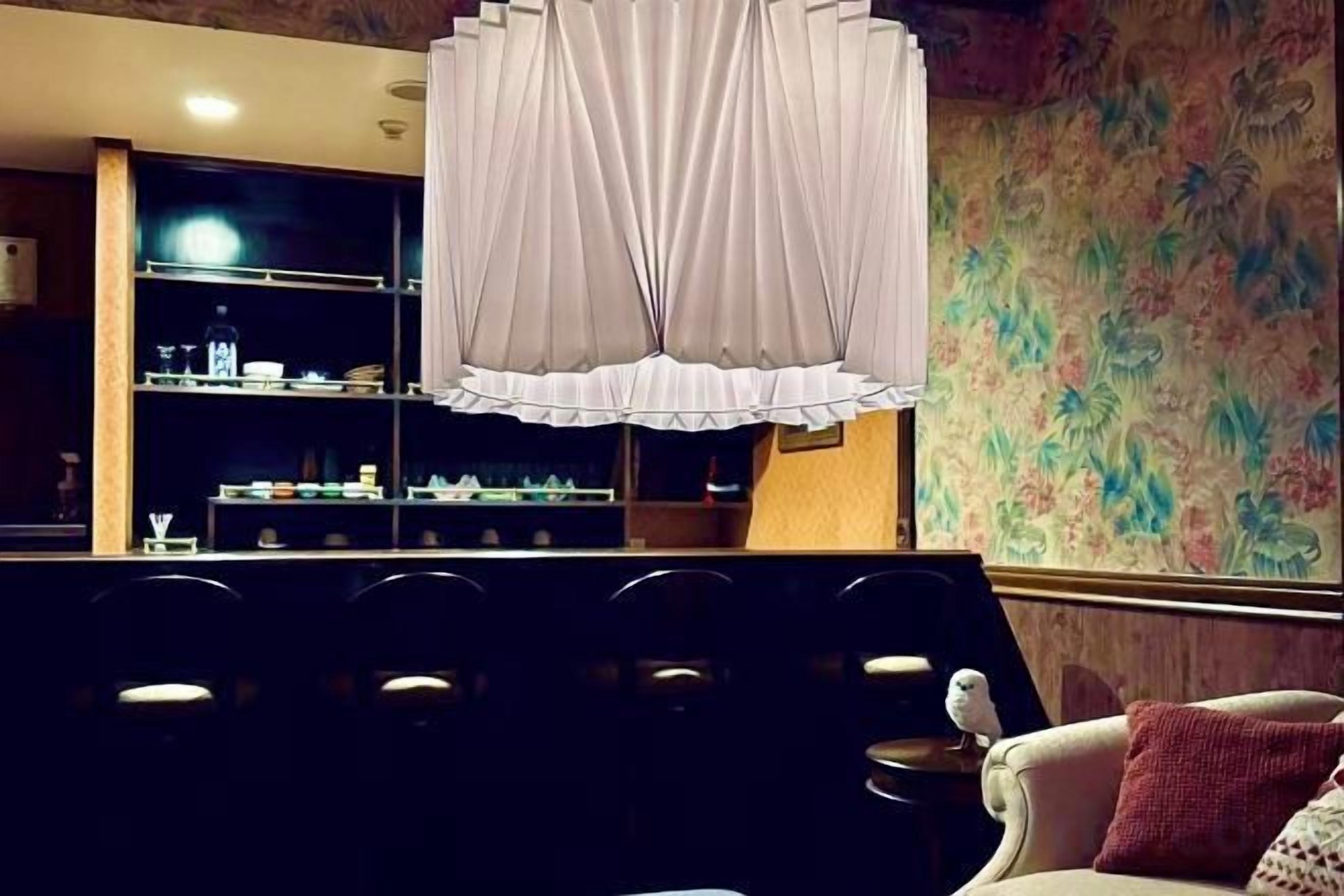 A room with a seating area, a chandelier, and a wall with floral wallpaper.