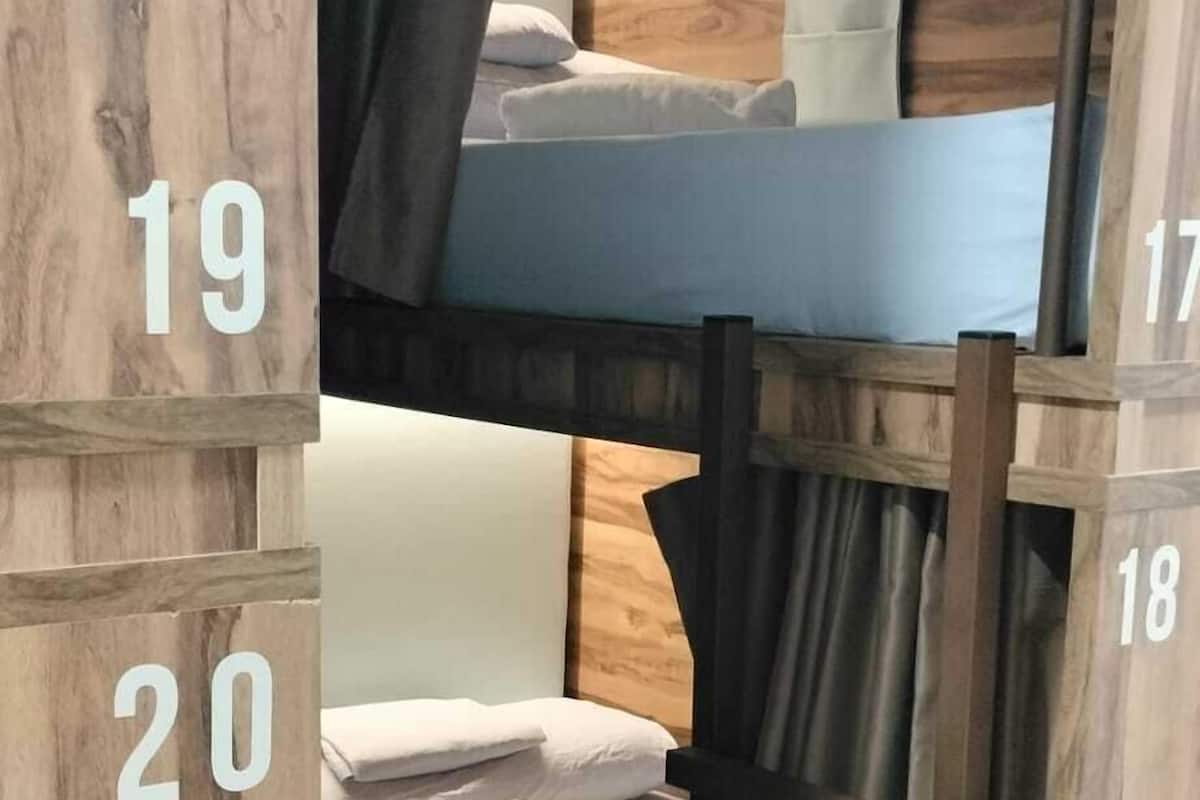 A bunk bed room with wooden walls, a small bedside table, and a curtain.