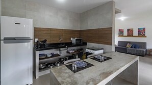 Cocina compacta con refrigerador, estufa, microondas y un frente de madera.