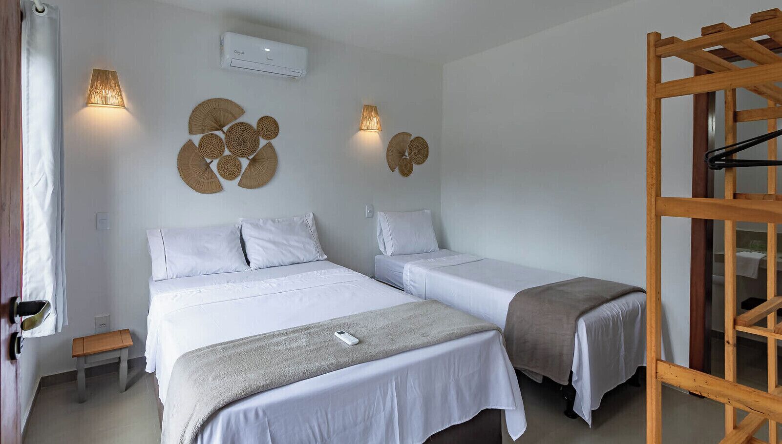 Habitación de hotel con dos camas, una escalera de madera y lámparas fijadas a la pared.