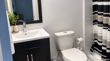 A modern bathroom with a white sink, black cabinets, a toilet, and a striped shower curtain.