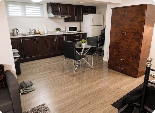 A compact kitchen with dark cabinets, a white refrigerator, and a dining area with a table and chairs.