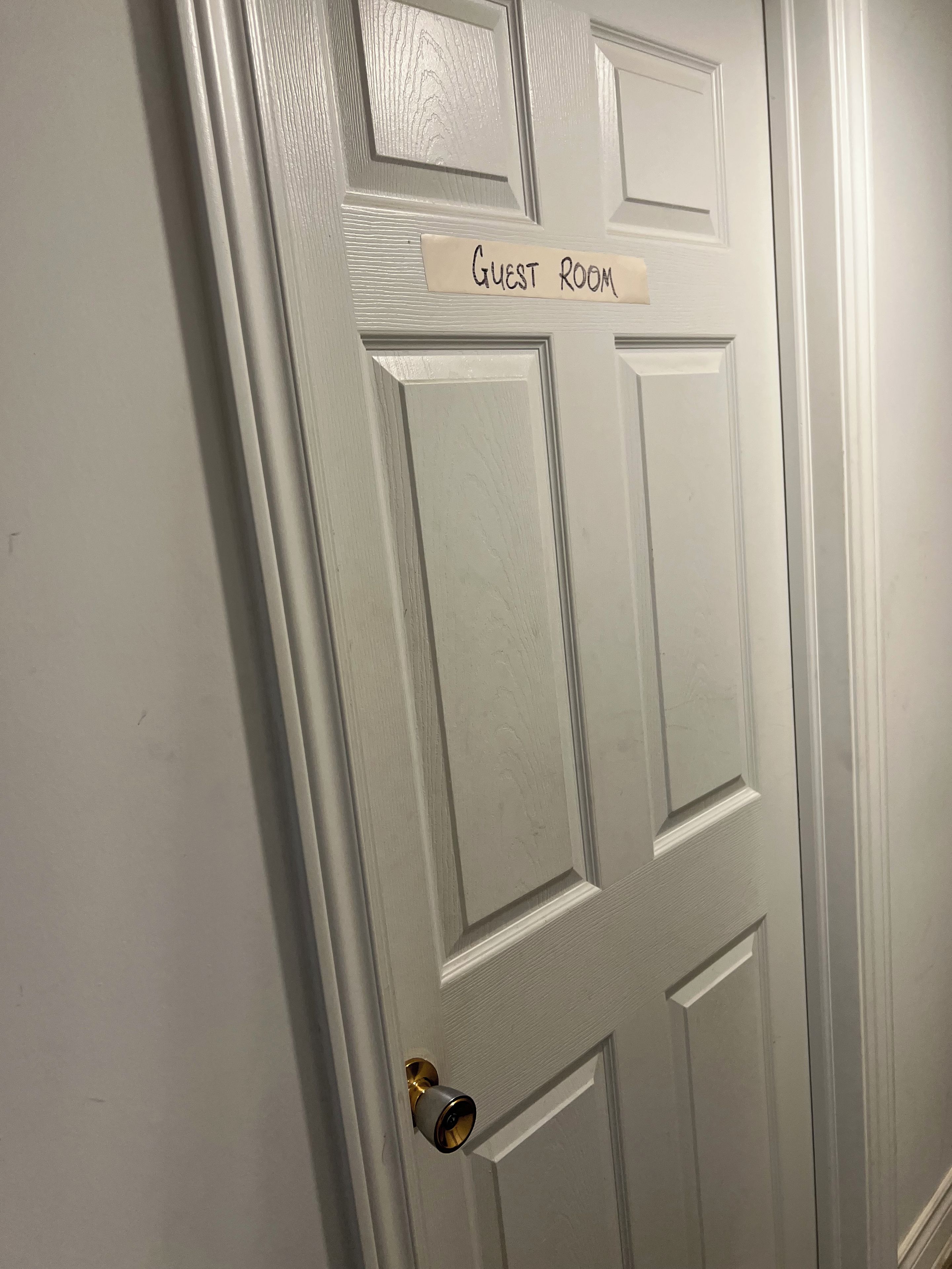 A white door with a sign reading 'Guest Room' and a doorbell.