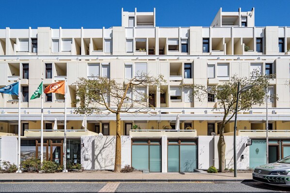 A modern multi-story building with a flat facade, balconies, and a gated entrance.