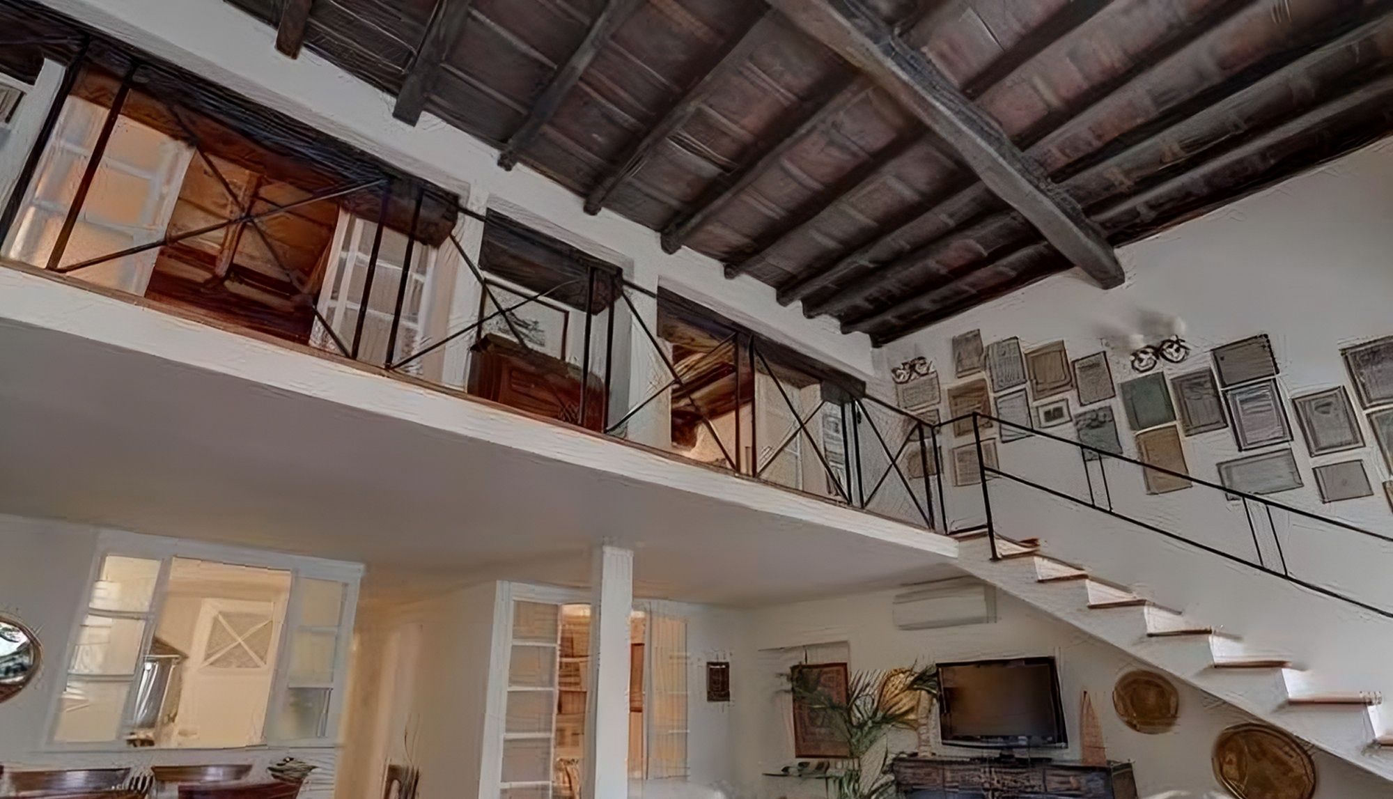 Ein großzügiger Wohnbereich mit Treppe, Holzboden und einem Fernseher auf einem Holzständer.