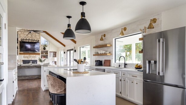 Cocina moderna con una isla grande, electrodomésticos de acero inoxidable, iluminación colgante y vistas al exterior.