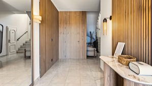 Un hall d’hôtel moderne avec un comptoir d’accueil, un mur recouvert de panneaux en bois et un escalier.