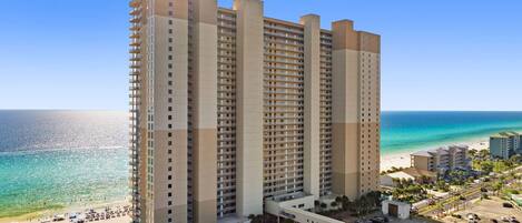 A high-rise hotel with multiple floors, a pool, and a beach view.