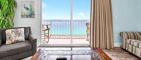 Ein Wohnzimmer mit Meerblick, einem Deckenventilator, einem Sofa, einem gestreiften Couch und einer Pflanze.