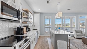 A modern kitchen with white cabinetry, a built-in oven, and a large window overlooking a balcony.