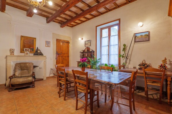 A dining area with a wooden table and chairs, a fireplace, and a large window. - Bed and Breakfast 'Fanny' with Shared Pool, Shared Garden and Wi-Fi (La Garde-Adhémar)