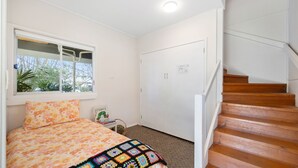Une chambre à coucher avec un lit, une fenêtre, une porte et un escalier en bois.
