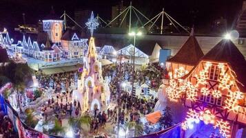 Un espacio exterior festivo con edificios iluminados y una multitud de personas.