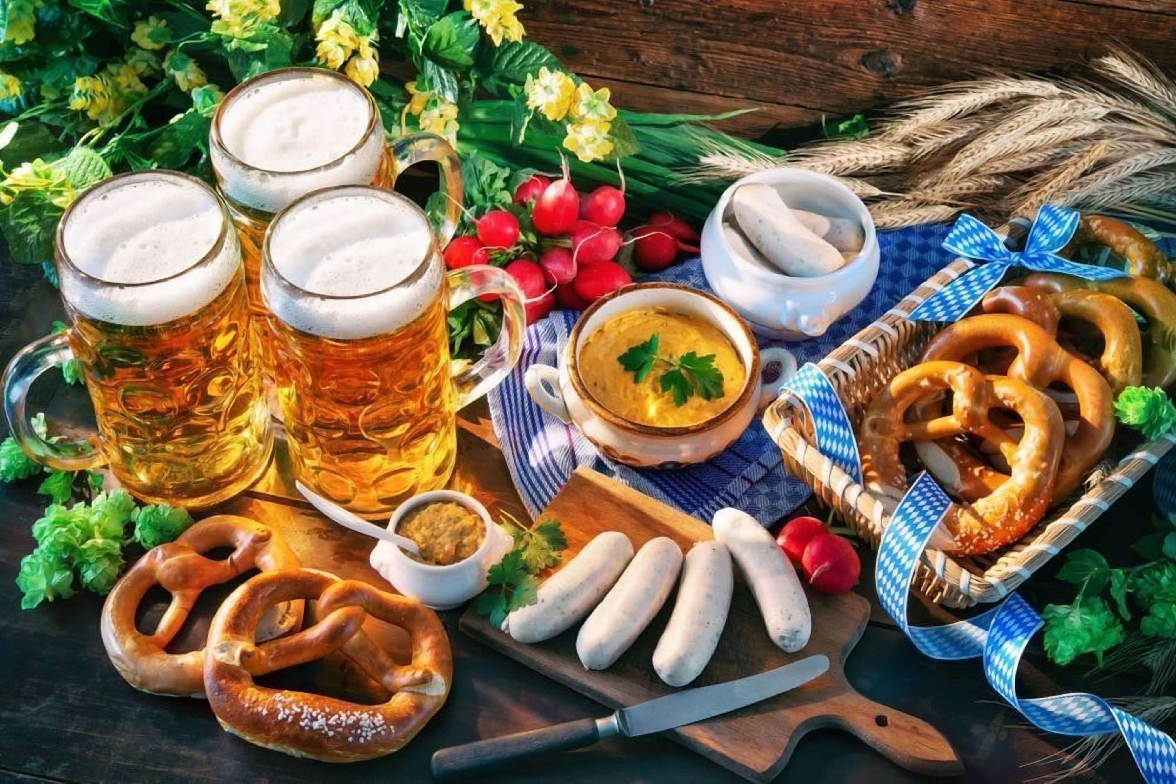 A table with beer mugs, pretzels, sausages, and a bowl of mustard.