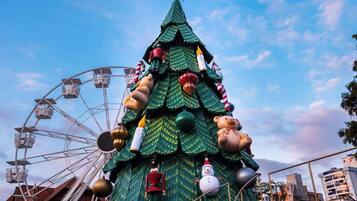 A large Christmas tree with ornaments and a star on top, set against a clear sky.
