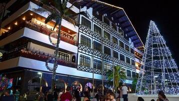 A multi-story hotel with balconies, a large Christmas tree, and a crowd of people.