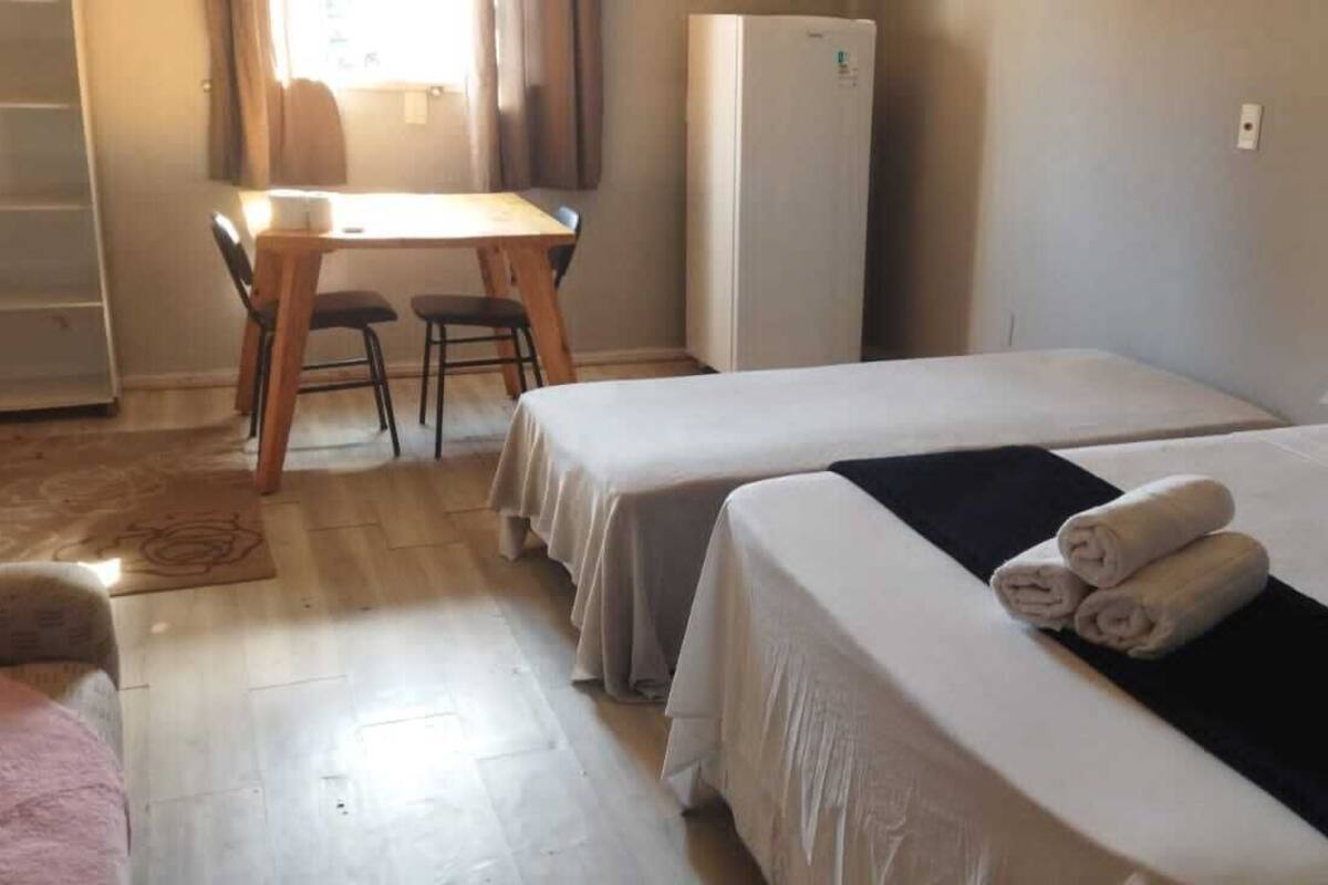 Une chambre d’hôtel avec deux lits, un bureau et un réfrigérateur.