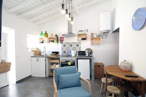 A modern kitchen with white cabinets, a wooden dining table, and a blue chair.