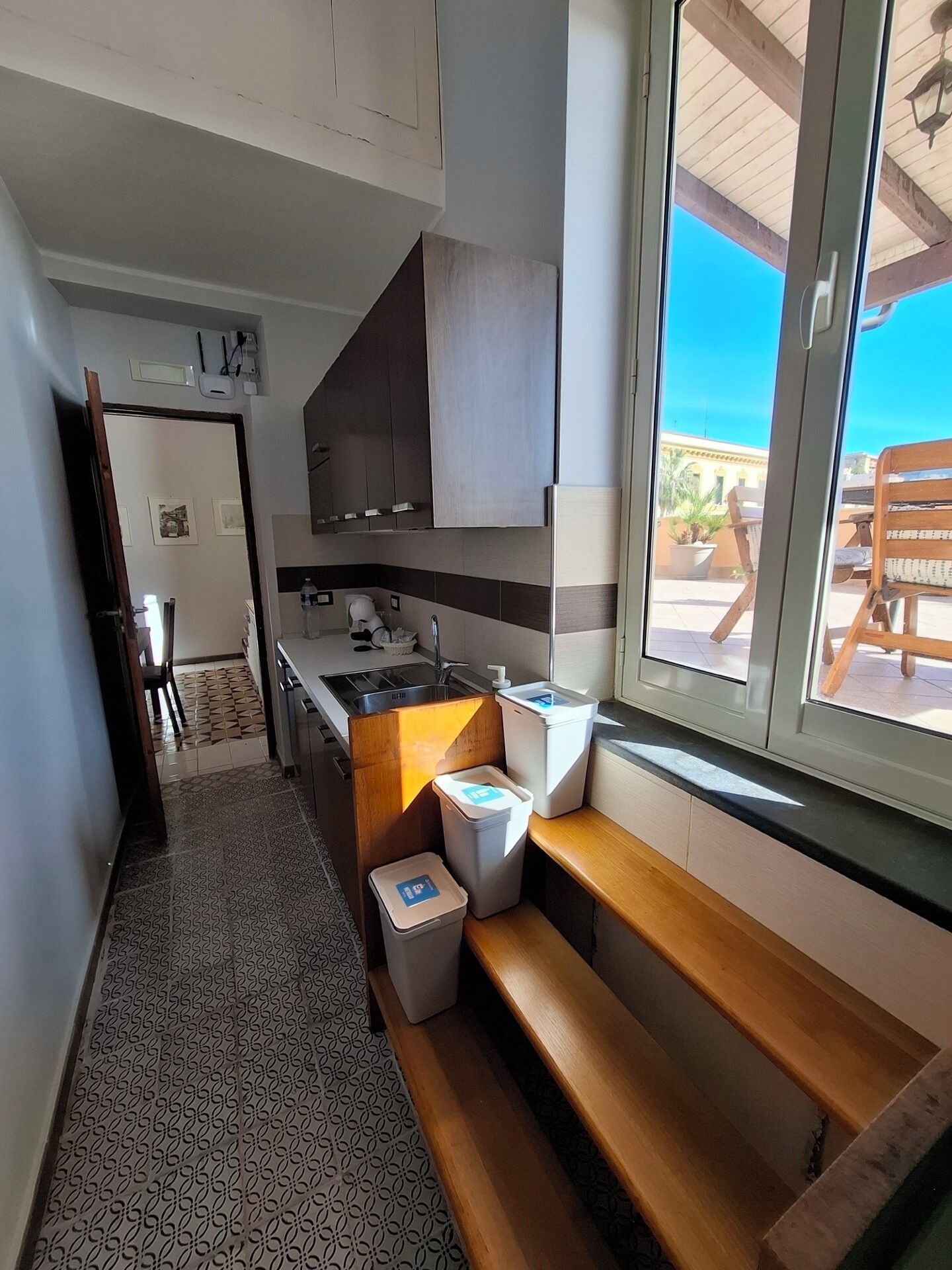 A modern kitchen with a large window, a wooden bench, and a view of the outdoors.