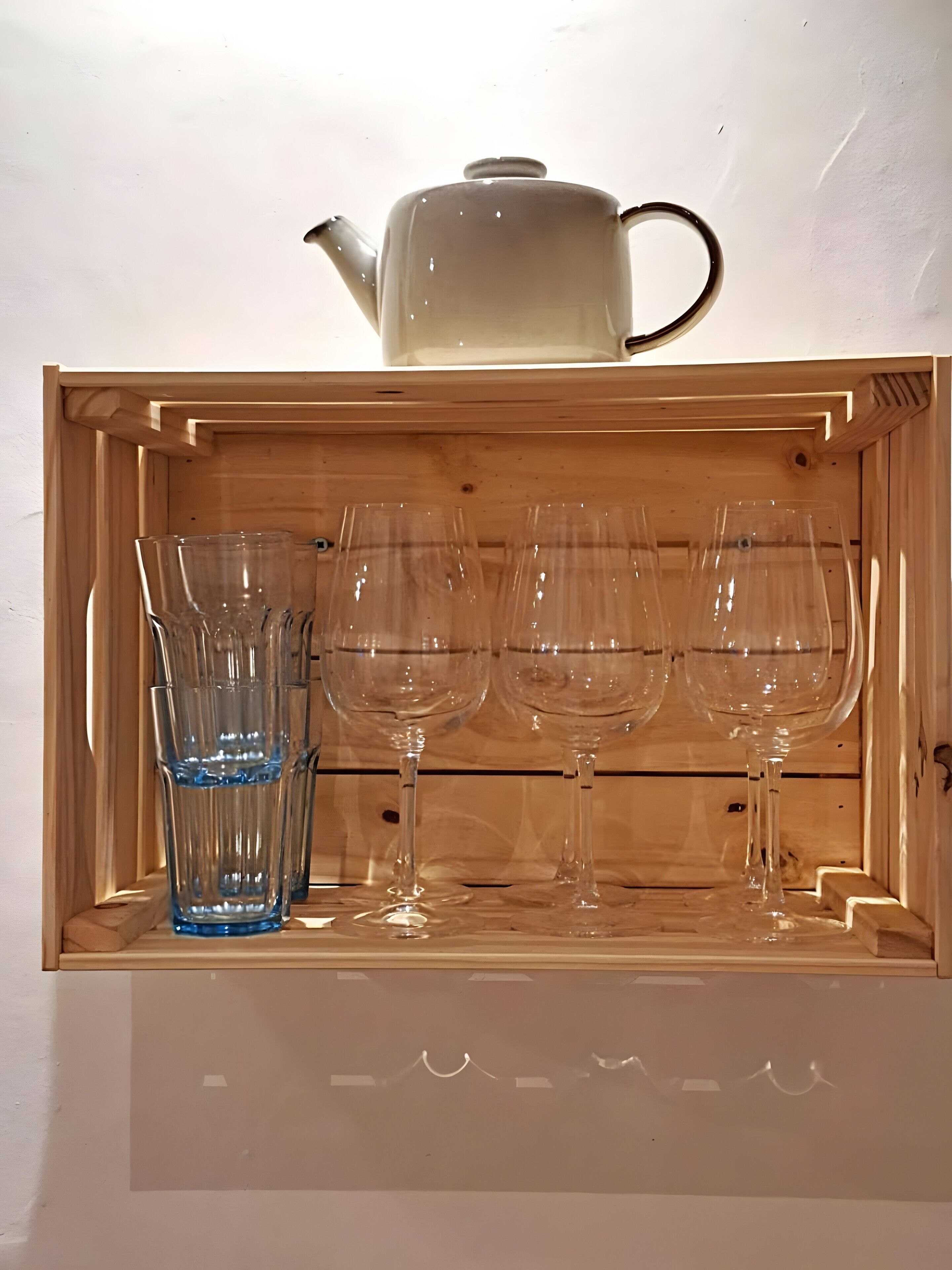 Un mueble de madera con un hervidor y cuatro copas de vino.