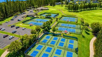 Vue aérienne d’un terrain de golf avec plusieurs courts de tennis et un parking.
