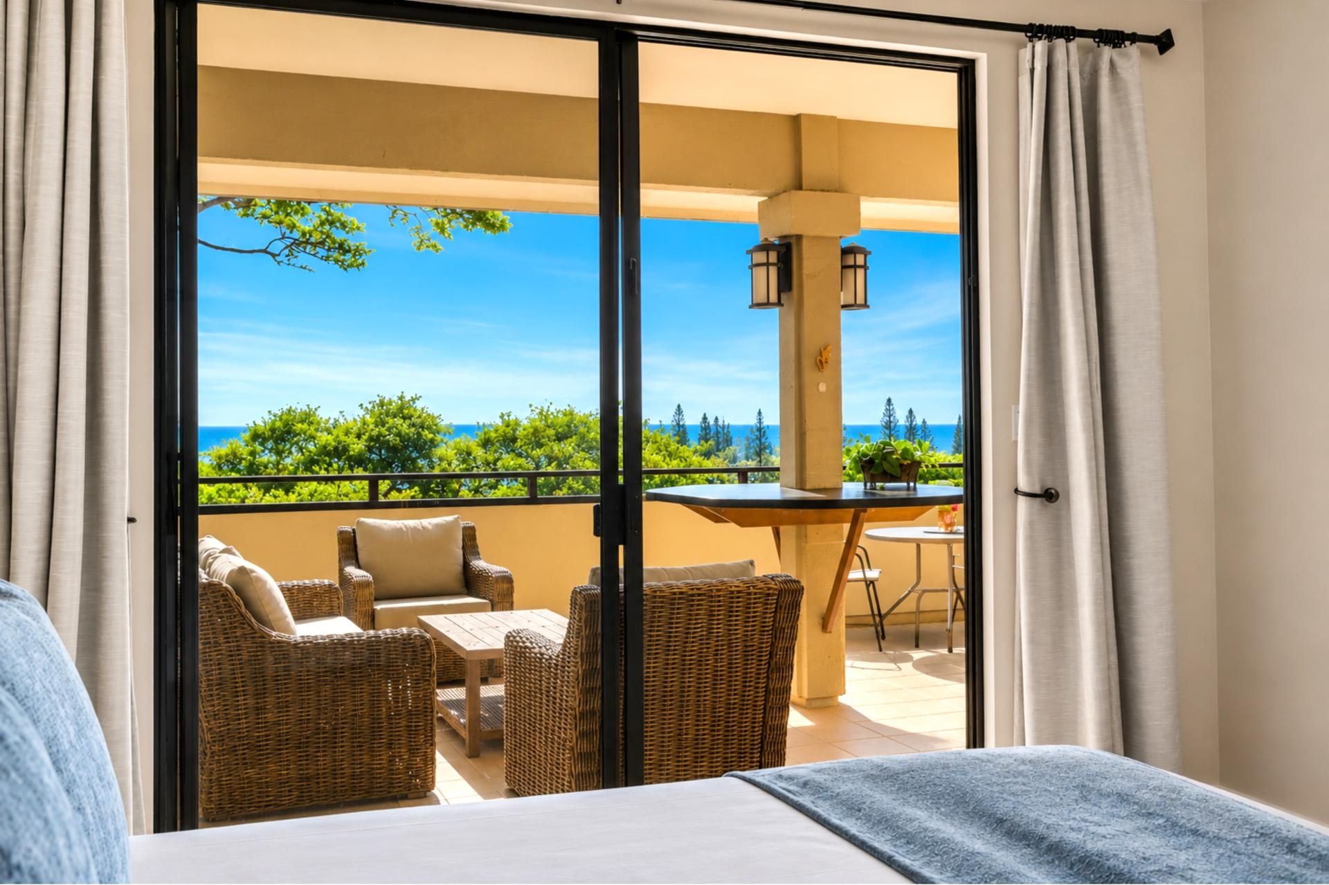 Een balkon met rieten meubels, een tafel en uitzicht op zee.