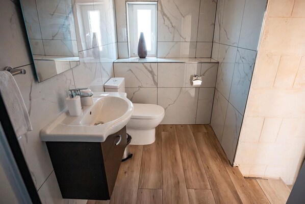 A modern bathroom with a sink, toilet, and mirror.