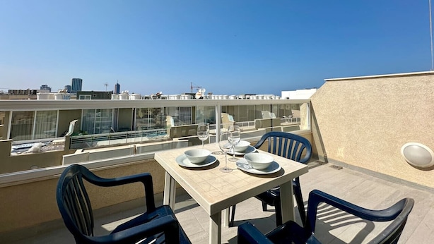Une terrasse sur le toit, avec une table dressée pour deux, offrant une vue sur le paysage urbain.
