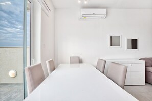 Ein moderner Besprechungsraum mit einem weißen Tisch, beigen Stühlen, einem weißen Schrank und einer Klimaanlage an der Wand.