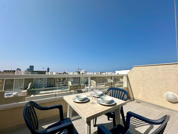A rooftop terrace with a table set for two, overlooking a cityscape. - Mercury Residence No.15 / Penthouse / Terrace (Sliema)