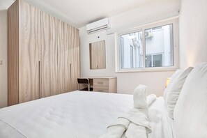 Una habitación de hotel con una cama, un armario de madera, un escritorio y una ventana.
