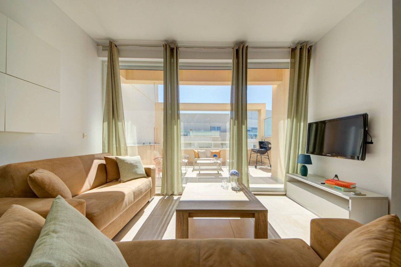 A modern living room with a sofa, a coffee table, and a TV mounted on the wall.
