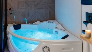 Ein modernes Badezimmer mit einer freistehenden Whirlwanne, einer Wand mit Holzstruktur und einem Spiegel mit blauem Rahmen.