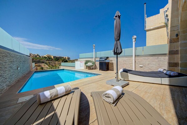 A rooftop pool area with lounge chairs, a grill, and a view of the surrounding landscape. - Oakville +, Private Pool & BBQ & Games Room (Xagħra)