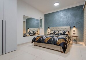 A modern bedroom with a large bed, a mirror, and a small table. - Oakville +, Private Pool & BBQ & Games Room (Xagħra)