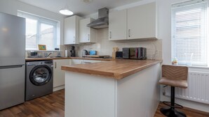 A modern kitchen with a built-in washing machine, a wooden countertop island, and a bar stool. - Pass the Keys | Modern | Office & Driveway | Near Crook & Durham (Crook)