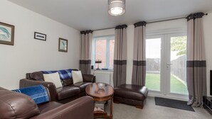 A furnished living room with a brown leather sofa, a wooden coffee table, and a window with curtains. - Pass the Keys | Modern | Office & Driveway | Near Crook & Durham (Crook)