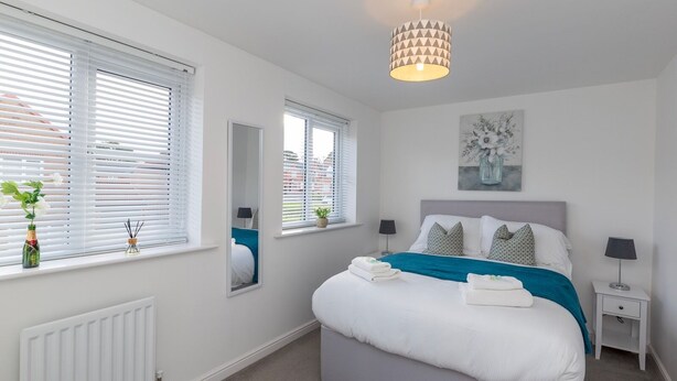 A bedroom with a bed, bedside tables, a radiator, and a ceiling light fixture. - Pass the Keys | Modern | Office & Driveway | Near Crook & Durham (Crook)
