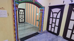 Un pasillo con un arco decorativo que conduce a una habitación con piso de baldosas y una puerta con diseño geométrico.