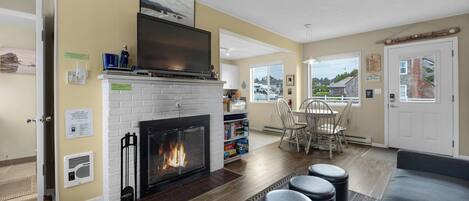 A living room with a fireplace, a dining area, and a view of the outside.