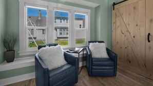 A room with two blue leather chairs with white fluffy pillows, a wooden floor, and a large wooden sliding door.
