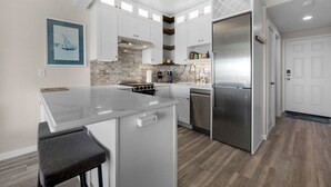 A modern kitchen with white cabinetry, a central island, and a stainless steel refrigerator.