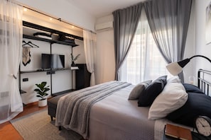 A modern bedroom with a bed, bedside lamp, and a TV on a shelf. - Kyntherland House The ideal location to immerse yourself in a relaxing vacation (Napoli)