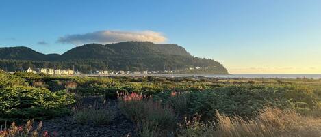 A coastal landscape with a mountain, a beach, and a town in the background.
