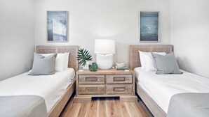 A hotel room with two beds, a nightstand with a lamp, and two framed pictures on the wall.