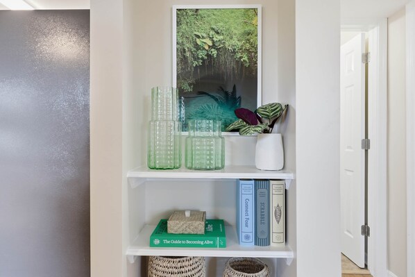 Une étagère blanche ornée d’objets décoratifs, d’un tableau encadré et de livres.